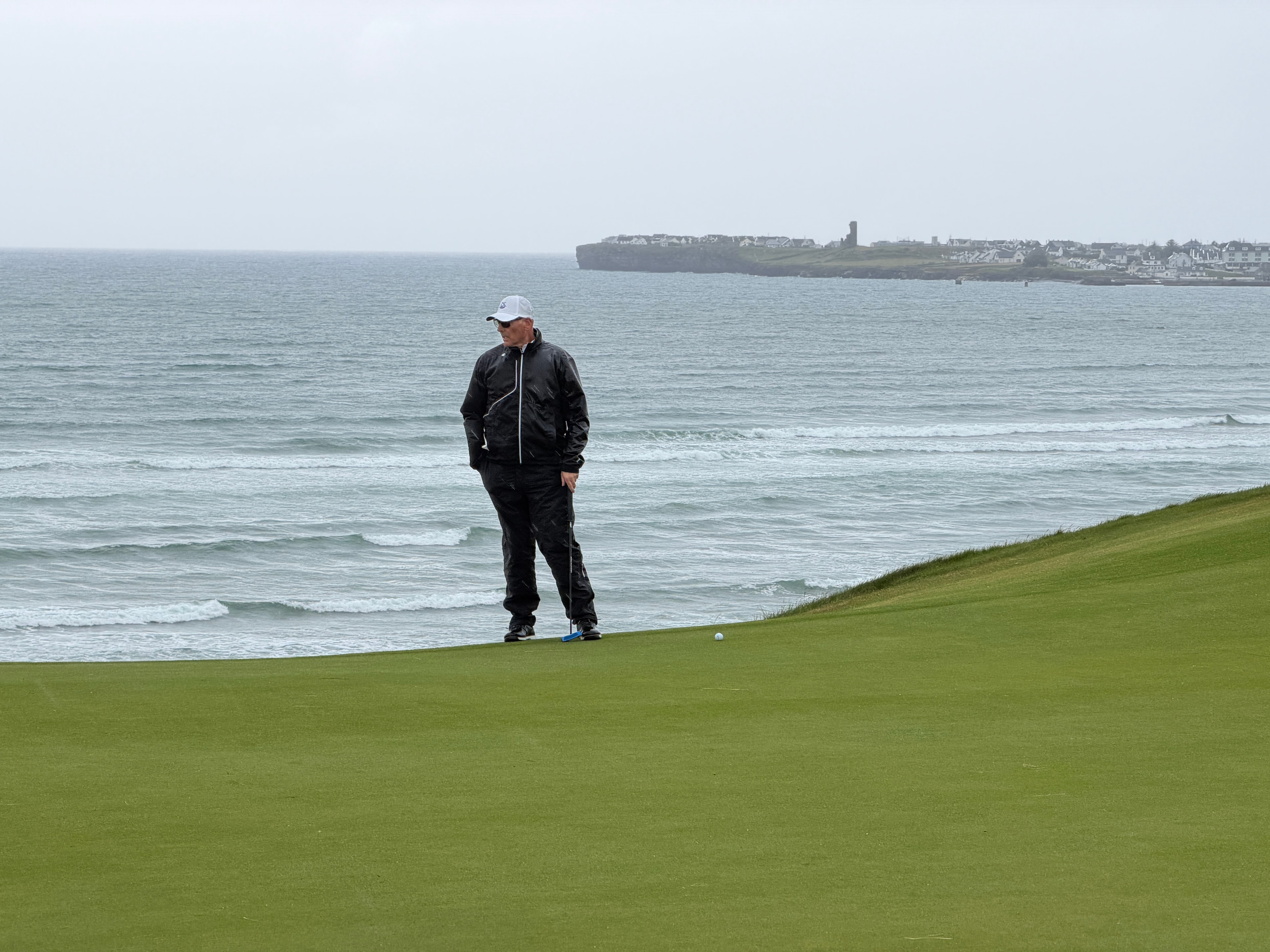 Scott on the green — Atlantic breakers and the town of Lahinch behind